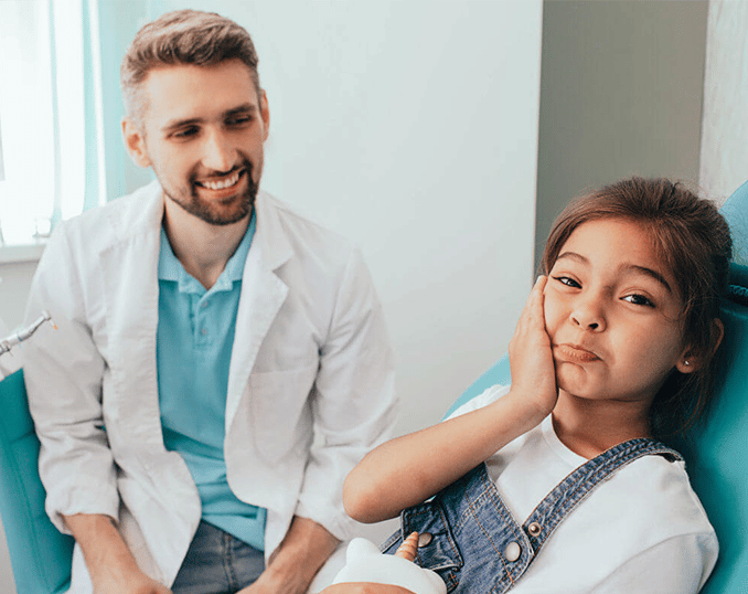 Two people in a medical office setting; one healthcare provider in light jacket standing beside seated patient.
