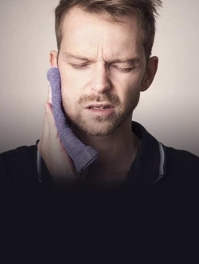 Man holding cold compress to jaw in pain, seeking immediate dental care.