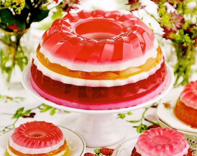 Layered gelatin desserts with fruit and cream on cake stands with floral decorations