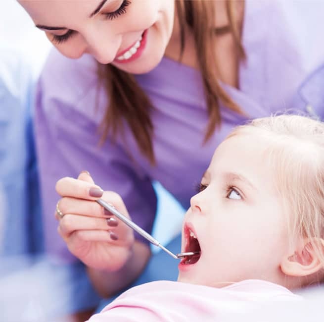 Pediatric dentist examining young child's teeth during dental appointment in Littleton.