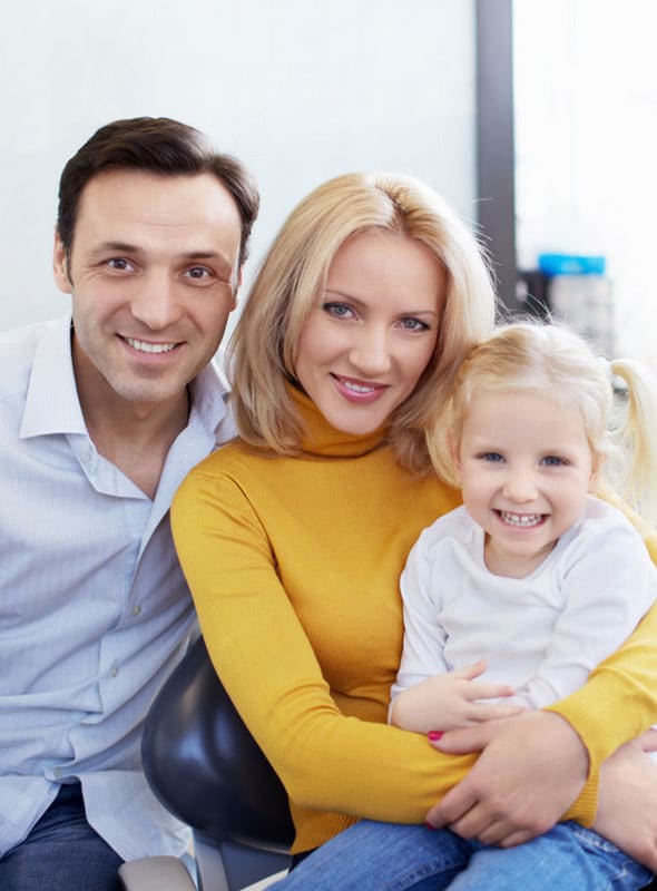 Happy family of three smiling together indoors in casual clothing