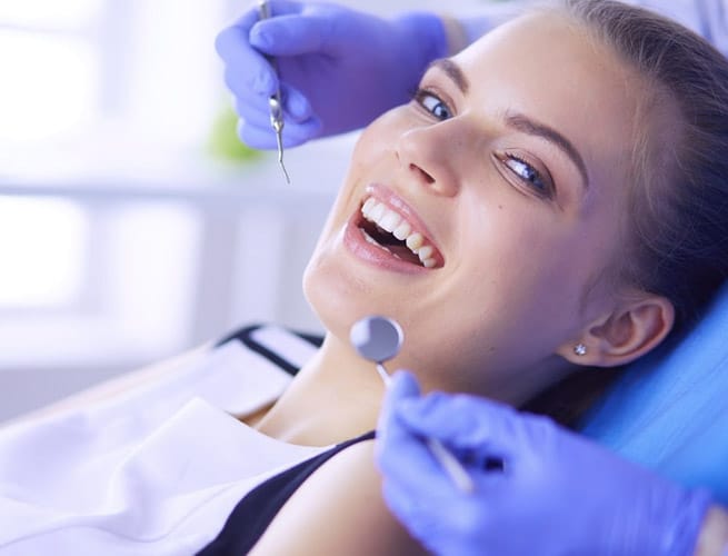 Dental professional examining patient's teeth during checkup in clinical office setting.