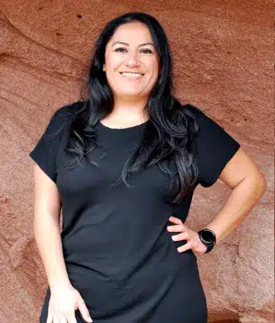 Professional portrait of a smiling female dentist standing outdoors, representing patient-centered dental care in Littleton, Colorado.